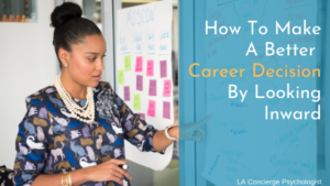 black woman with hair in bun and colorful blouse pointing at white board